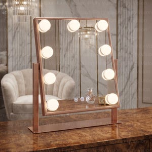 May include: A rectangular vanity mirror with a rose gold frame and ten integrated round LED bulbs. The mirror features a flat base and touch-sensitive controls on the glass surface marked with N, a heart icon, and P, reflecting a perfume bottle.