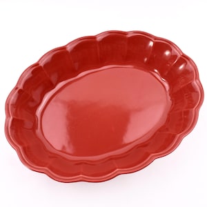 May include: A glossy, oval-shaped serving platter in a vibrant red hue. The platter features a scalloped edge, adding a decorative touch to its design. This dish is suitable for serving food.