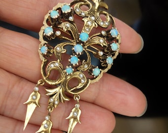 May include: A gold pendant with a delicate floral design featuring blue opals and pearls. The pendant has three dangling teardrop-shaped charms.