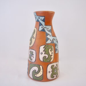 May include: A terracotta vase with a geometric pattern in shades of blue, green, and white. The vase has a rounded body and a narrow neck.
