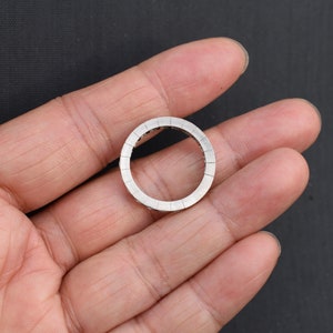 May include: A silver ring with a round design. The ring is set with small, clear stones that create a sparkling effect.