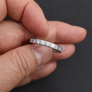 May include: A thin silver band with small round diamonds set in a pave setting.