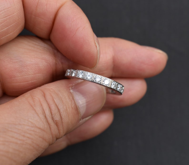 May include: A thin silver band with small round diamonds set in a pave setting.