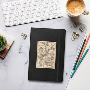 May include: A black leather-bound journal with a vintage map of the Caribbean islands printed on the front cover. The map is in shades of brown, red, and green.