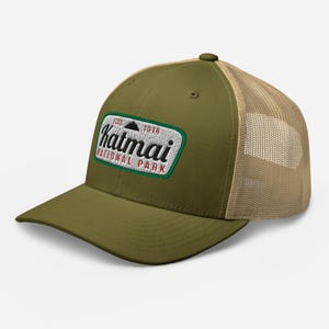 May include: A green and tan trucker hat with an embroidered patch that says "Katmai National Park" with the years 1917 and 1978.