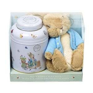 May include: A white ceramic tea caddy with a Peter Rabbit design and a blue and white Peter Rabbit plush toy. The tea caddy has a Peter Rabbit illustration on the front and the text "Peter Rabbit Tea Caddy with 80 English Breakfast Teabags".