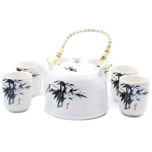 Peut inclure: Service à thé en céramique blanche comprenant une théière et quatre tasses assorties. La théière a une anse tressée et est décorée de bambous noirs et de calligraphie rouge. Les tasses présentent également le motif de bambou.