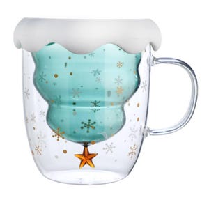 May include: A clear glass mug with a teal-colored, Christmas tree-shaped interior. The mug has a white, wavy rim and a gold star at the bottom. Gold snowflakes and dots decorate the exterior. A clear handle is attached.
