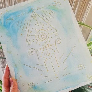 K&ouml;nnte beinhalten: Ein rechteckiges Blatt Papier mit einem Aquarellverlauf in Hellblau und Gr&uuml;n. Die Oberfl&auml;che ist mit goldenen Tuschezeichnungen verziert, die aus einem zentralen Dreieck, Spiralen, Punkten und vertikal angeordneten geometrischen Symbolen bestehen.