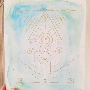 K&ouml;nnte beinhalten: Ein rechteckiger Kunstdruck mit einem Aquarellverlauf in Hellblau und Hellgr&uuml;n. &Uuml;ber dem Aquarell befindet sich eine symmetrische Illustration in Goldtinte, bestehend aus einem zentralen Dreieck, Spiralen, Punkten und geometrischen Linien.
