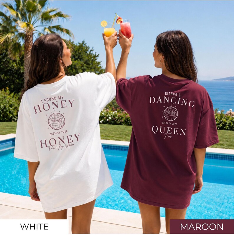 May include: Two oversized t-shirts, one white and one maroon, with text on the back. The white shirt says "I FOUND MY HONEY" with "DRESDEN 2026" and "HONEY" below. The maroon shirt says "BIANCA'S DANCING QUEEN" with "DRESDEN 2026" and "Joly" below.