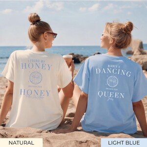 May include: Two t-shirts, one natural and one light blue, with text and a globe design. The natural shirt says "I FOUND MY HONEY" and "HONEY". The light blue shirt says "BIANCA'S DANCING QUEEN". Both shirts say "DRESDEN 2020".