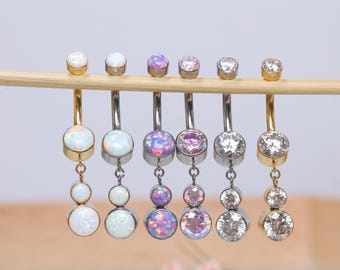 May include: A set of six belly button rings with different colored gems. The rings are made of surgical steel and have a dangle charm. The gems are opal, clear, and pink.