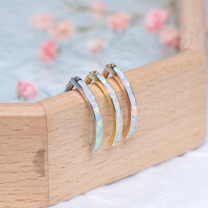 May include: Three hoop earrings with a white opal inlay. The hoops are made of silver, gold, and rose gold.