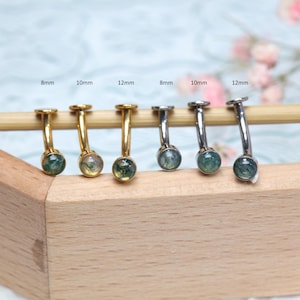 Puede incluir: Seis pequeñas piezas de joyería decorativas con una gema circular al final de una barra de metal curvada. Tres son doradas y tres plateadas. Las gemas son verdes y claras. Los tamaños son 8 mm, 10 mm y 12 mm.