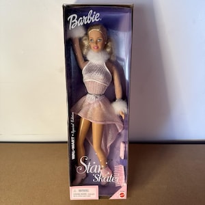 May include: A Barbie doll in a clear plastic box. The doll is wearing a pink ice skating outfit with a white fur collar and cuffs. The box reads "Barbie" and "Star Skate" with "WALMART + Special Edition" text.