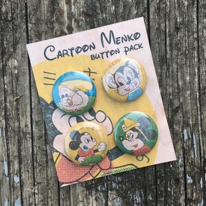 May include: A set of four vintage cartoon character button pins. The pins feature Mickey Mouse, Minnie Mouse, a cat, and a man with a mustache. The pins are on a yellow card with the text "Cartoon Menko Button Pack".