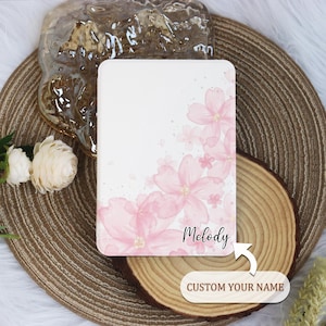 May include: A white background with a pink watercolour design of cherry blossoms. The name "Melody" is written in black cursive at the bottom of the design. The text "CUSTOM YOUR NAME" is written below the design.