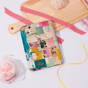 May include: A rectangular tablet case with a collage design featuring vintage postcards, stamps, and a butterfly. The case has a teal border and is surrounded by a wooden cutting board, red and white ribbon, and a small cake.