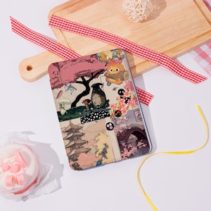 May include: A multi-panel case featuring illustrations of characters and scenes from a Japanese animated film. The design includes a pagoda, a bridge with cherry blossoms, and various animated characters in a colourful, whimsical style.