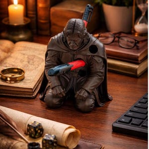May include: A dark brown resin figurine of a kneeling figure in a cloak, designed as a desk organizer. The figure features circular openings in the chest and shoulder areas, currently holding two red and black pens in a horizontal and vertical position.