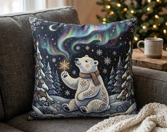 May include: A square throw pillow featuring a white polar bear wearing a brown scarf, sitting in a snowy forest landscape. The scene includes stylized evergreen trees, falling snowflakes, a crescent moon, and vibrant green and purple aurora borealis.
