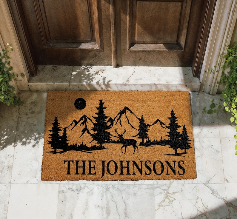 A mat with a mountain landscape and a deer silhouette, with the text "THE JOHNSONS" printed on it.