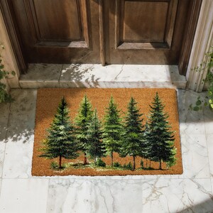 A decorative mat with a forest scene on it, placed on a tiled floor in front of a wooden door.