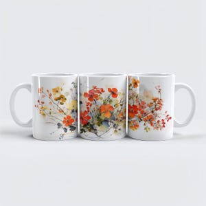 May include: Three white ceramic mugs with a floral watercolor design. The design features orange, yellow, and red flowers with green stems and leaves. The mugs have a standard handle and a glossy finish.