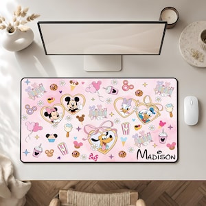May include: A rectangular desk mat with a light pink background featuring a repeating pattern of Disney characters including Mickey, Minnie, Donald, Daisy, and Pluto inside heart-shaped frames, alongside icons of balloons, treats, and the name Madison.