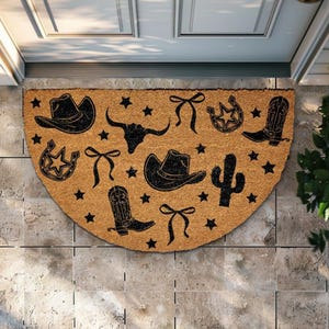May include: A half-circle doormat made of natural coir fiber. The mat features black cowboy-themed designs, including cowboy hats, boots, a bull skull, stars, bows, a horseshoe, and a cactus. The mat is placed in front of a door.