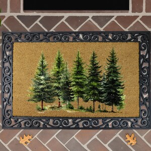 a decorative mat with a painting of a group of pine trees on it, placed on a brick wall.