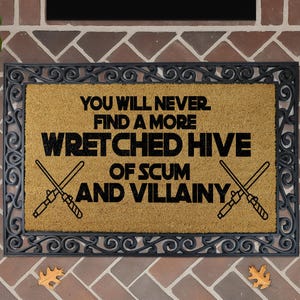 a humorous sign with the text "You will never find a more WRETCHED HIVE of SCUM and VILLAINY" on a decorative doormat.