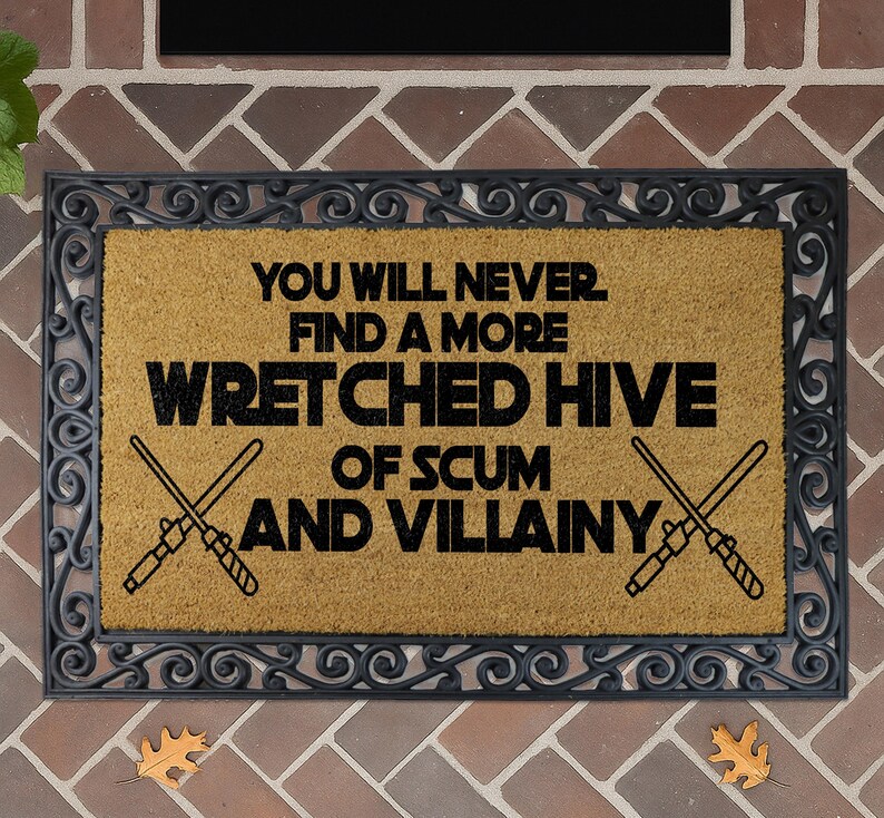 a humorous sign with the text "You will never find a more WRETCHED HIVE of SCUM and VILLAINY" on a decorative doormat.