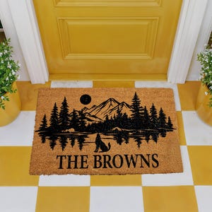 A yellow door with a mat featuring a mountain landscape and a wolf silhouette, with the text "THE BROWNS" printed on it.