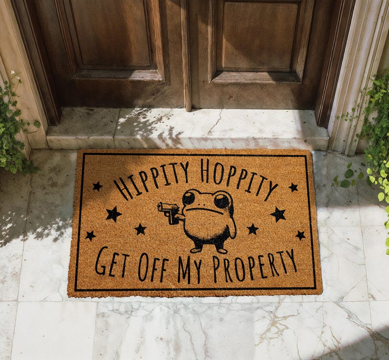 A door mat with a cartoon frog holding a gun and the text "Hippity Hopperity Get off my property" printed on it.