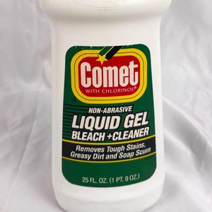 May include: White Comet Liquid Gel Bleach + Cleaner bottle with a green cap and label. The label includes the brand name, product type, and the text "Removes Tough Stains, Greasy Dirt and Soap Scum". The bottle contains 25 fl. oz.