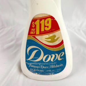 May include: A vintage white plastic bottle of Dove dishwashing liquid. The bottle has a blue cap and a label with the Dove logo and the text "Famous Dove Mildness". The label also includes the price $1.19.