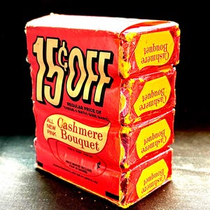 May include: A vintage red box of Cashmere Bouquet soap with a yellow and black label. The box is marked "15¢ OFF" in large yellow letters. The box contains four individual soap bars.