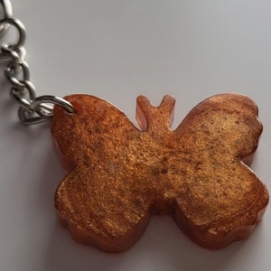 May include: A gold metallic butterfly keyring with a silver chain and ring.