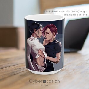 May include: A white ceramic mug featuring a digital illustration of two individuals. One person wears a white long-sleeved top, and the other wears a black short-sleeved shirt with arm tattoos. The text on the mug reads: Model shown is the 15oz (444ml) mug - also available in 11oz.
