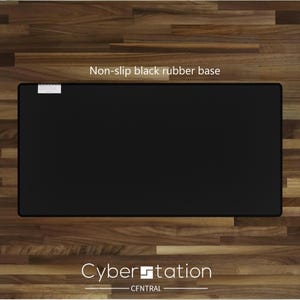 Op de afbeelding: Een rechthoekige zwarte antislip rubberen basis met de tekst "Non-slip black rubber base" en "Cyber Station CENTRAL" in het wit. De basis ligt op een houten oppervlak.