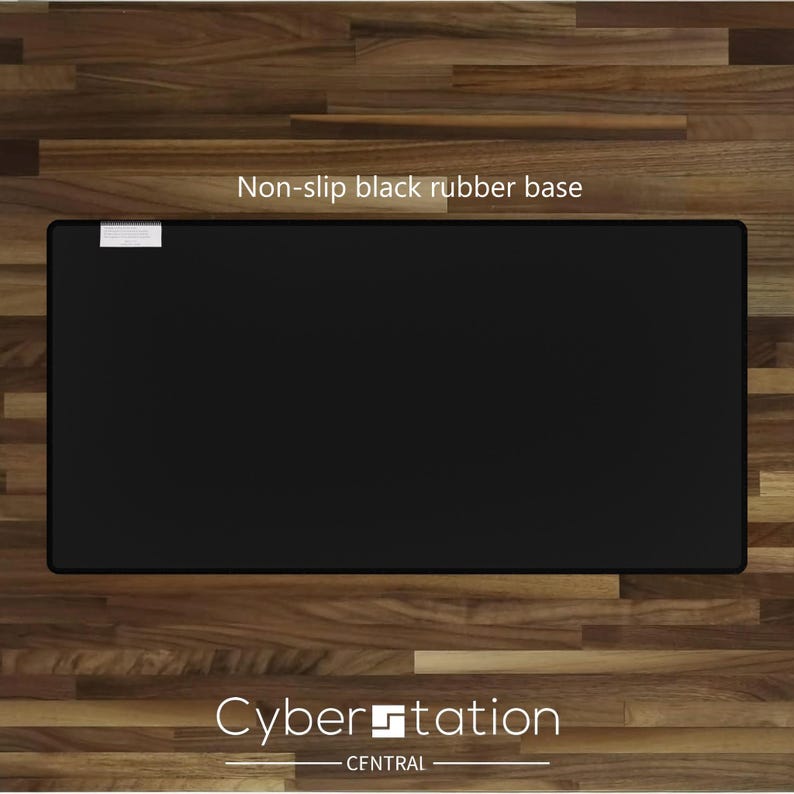 Op de afbeelding: Een rechthoekige zwarte antislip rubberen basis met de tekst "Non-slip black rubber base" en "Cyber Station CENTRAL" in het wit. De basis ligt op een houten oppervlak.