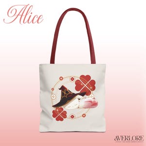 May include: Cream-colored tote bag with a whimsical illustration of a character wearing a witch hat and sleeping. The bag has burgundy handles and the name "Alice" in cursive. Red and gold clover and cross designs surround the character.