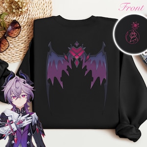 Peut inclure: Sweat-shirt noir avec un motif d'ailes de chauve-souris violet et rose. Un motif circulaire plus petit est sur le coin supérieur droit. Le mot "Front" est écrit en rose en haut.