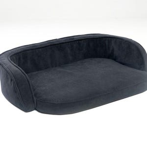 May include: A dark grey pet bed with a curved back and sides. The bed has a soft, plush appearance and is designed for comfort. The overall shape is rectangular with rounded edges, suitable for small to medium-sized pets.
