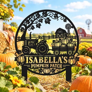Puede incluir: Un letrero de jardín circular de metal negro con un tractor que tira de un carro lleno de calabazas, un granero, un molino de viento y hojas de arce. El texto ISABELLA'S PUMPKIN PATCH aparece en letras doradas, con dos estacas inferiores.