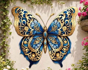 Puede incluir: Un adorno de pared en forma de mariposa con intrincados patrones de filigrana dorada sobre alas de color azul profundo. La mariposa tiene un cuerpo central dorado con detalles azules y alas simétricas con motivos de volutas.