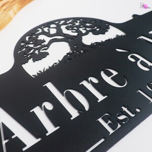 May include: Black metal sign with a cut-out tree design. The sign features the word "Arbre" and "Est. 19". The tree silhouette is detailed, and the sign is mounted on a white background.