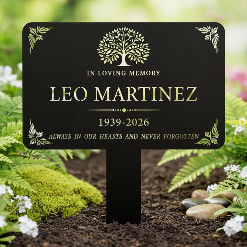 Puede incluir: Una estaca de jard&iacute;n conmemorativa negra con el nombre "LEO MARTINEZ" y las fechas 1939-2026 en letras doradas. La estaca tiene un dise&ntilde;o de &aacute;rbol y las palabras "IN LOVING MEMORY" y "ALWAYS IN OUR HEARTS AND NEVER FORGOTTEN".